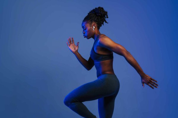 african american female jogging against dark blue background, side view